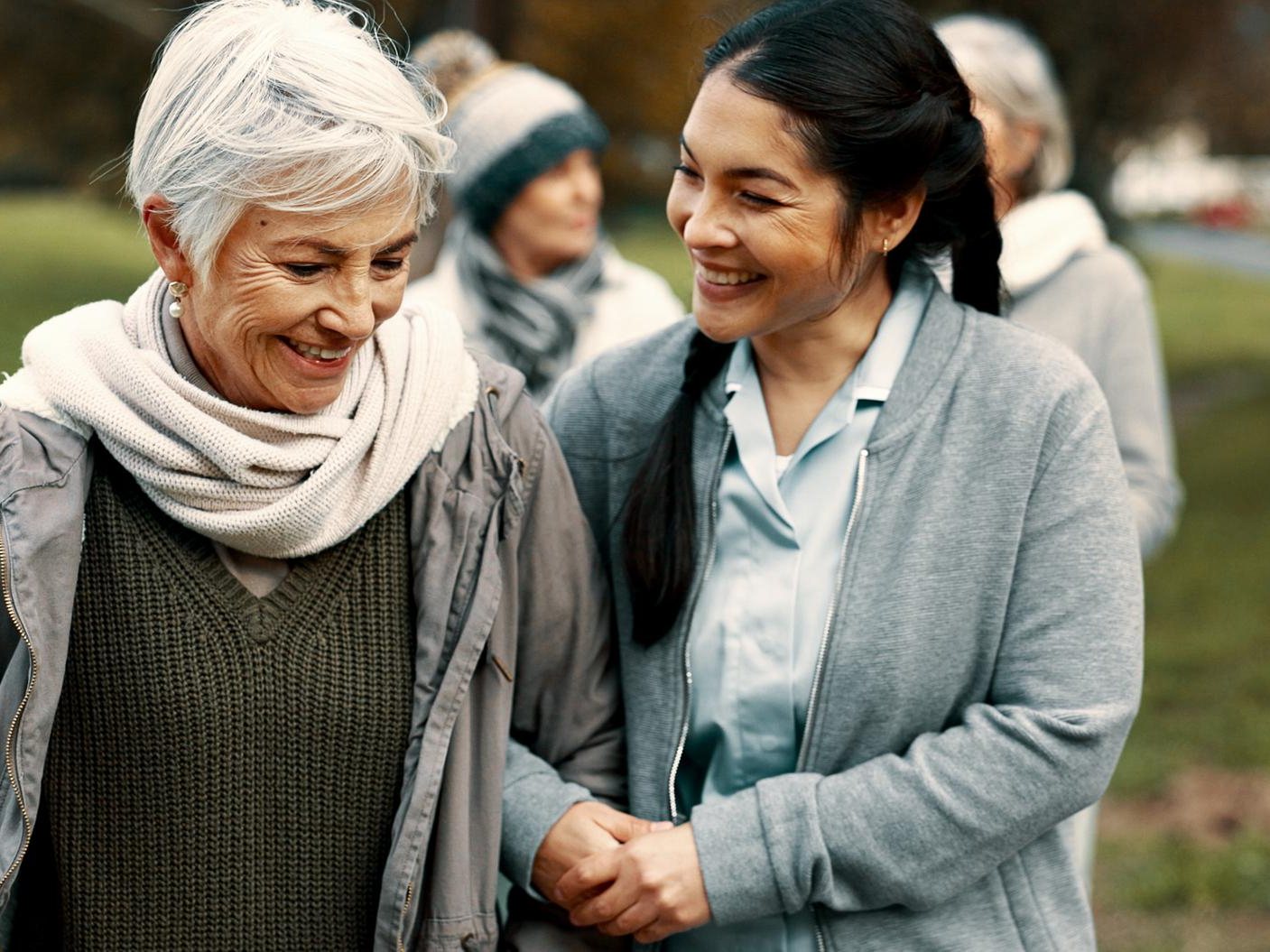 A care worker walking outdoors with an older woman