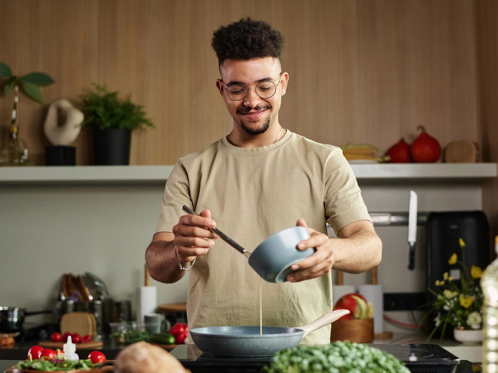 A young man cooking a meal in his own kitchen
