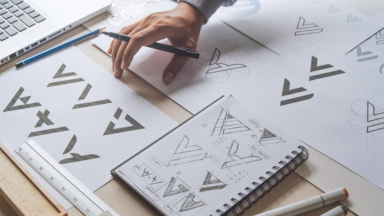 Hand-drawn logo studies and brand sketches on a designer's desk