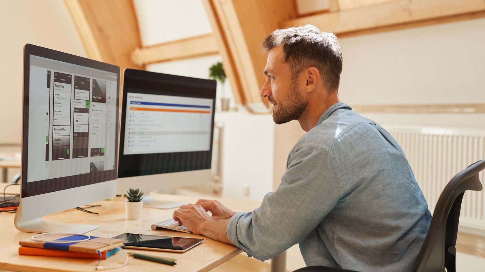 A designer reviewing a website layout on screen in a warm, sunlit workspace